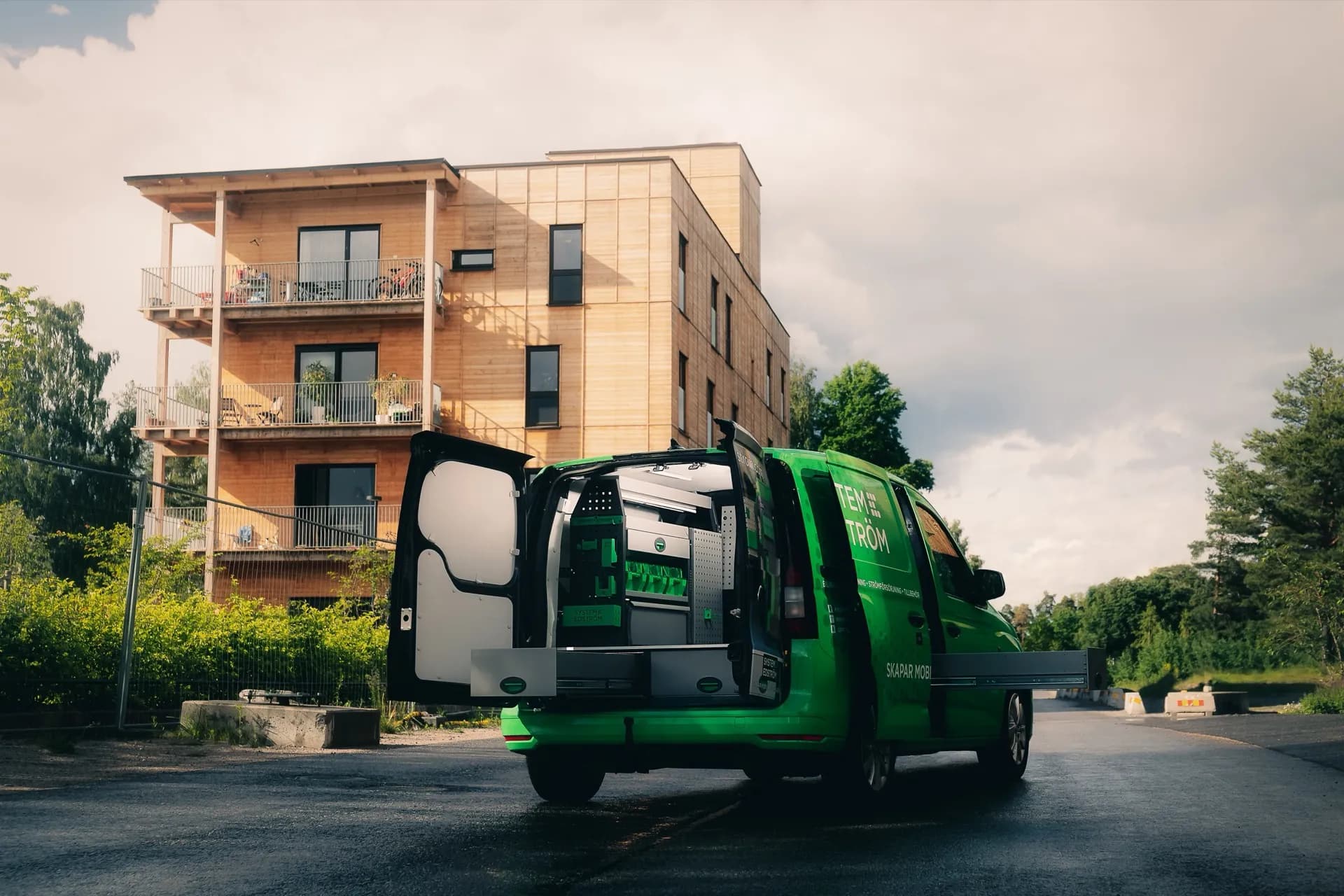 Servicebil med öppen bilinredning vid bostadshus